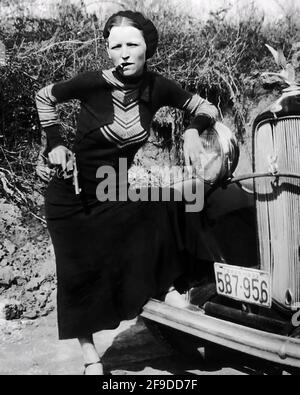 1934, Arkansas, USA: BONNIE mit Revolver raucht eine Zigarre. Des berühmten Gangsterpaares BONNIE PARKER ( 1910 - 1934 ) und CLYDE BARROW ( 1909 - 1934 ). Entgegen der landläufigen Meinung haben die beiden nie geheiratet. Sie waren in einer langjährigen Beziehung. Vor einem Ford V8-Automobil von 1932 posiert, wo Bonnie und Clyde am 23. Mai 1934 starben. Unbekannter Fotograf. - OUTLAWS - KILLER - ASSASSINO - delinquente - criminalità organizzata - GANGSTERN - Bos - CRONAKA NERA - CRIMINALE - Auto - Automobil - Hut - cappello - sigaro - Fumo - Rauch - Fumatore - Frau Raucher - fumat Stockfoto