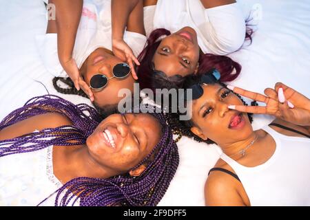 Die vier jungen afroamerikanischen Frauen, die sich im Bett amüsieren Stockfoto