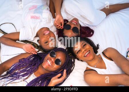 Die vier jungen afroamerikanischen Frauen, die sich im Bett amüsieren Stockfoto