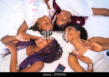 Die vier jungen afroamerikanischen Frauen, die sich im Bett amüsieren Stockfoto