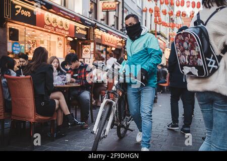 Soho, London - 2021.04.16: Deliveroo Mann Fahrer mit einem Fahrrad wartet auf neue Bestellung. Lieferservice Stockfoto
