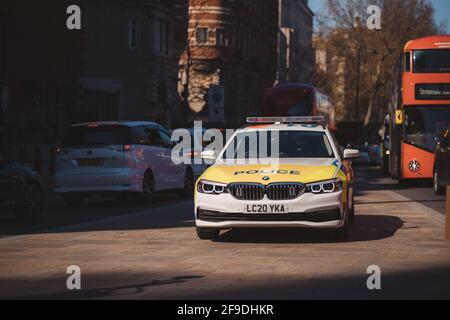 Westminster, London - 2021.04.17: Polizeiauto BMW parkte auf dem Bürgersteig neben dem roten Doppeldeckerbus Stockfoto