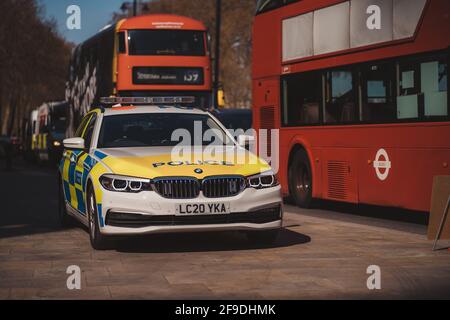 Westminster, London - 2021.04.17: Polizeiauto BMW parkte auf dem Bürgersteig neben dem roten Doppeldeckerbus Stockfoto