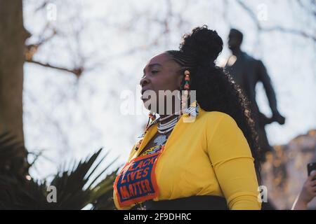 Westminster, London - 2021.04.17: Lady in gelbem Kostüm mit Black Lives Matter-Schild, das beim Protest „Kill the Bill“ einen Spusch ausgibt Stockfoto