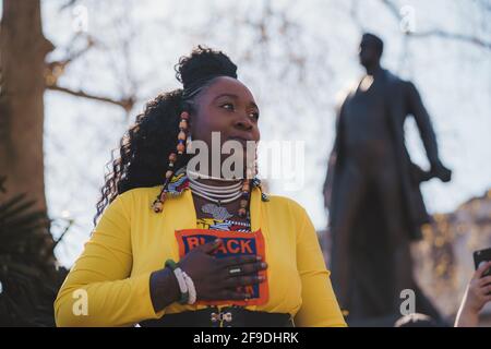 Westminster, London - 2021.04.17: Lady in gelbem Kostüm mit Black Lives Matter-Schild, das beim Protest „Kill the Bill“ einen Spusch ausgibt Stockfoto