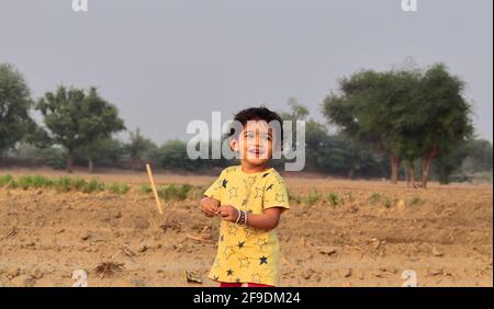 Nahaufnahme eines kleinen indischen Jungen, der lächelt und steht In der Landwirtschaft Stockfoto