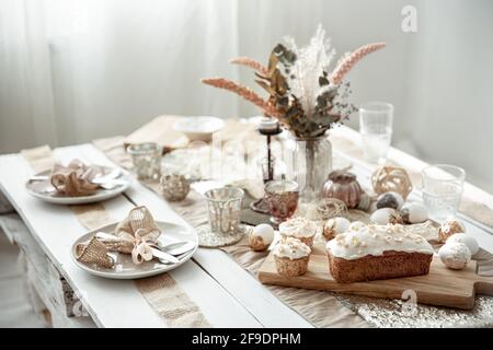 Ein festlicher Tisch mit schöner Kulisse, dekorativen Details, Eiern und Osterkuchen. Stockfoto