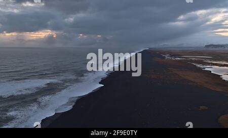 Atemberaubende Luftaufnahme über die Südküste Islands mit schönem schwarzen Sandstrand mit starker Brandung und den Ausläufern von Mýrdalsjökull. Stockfoto