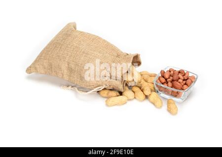 Erdnüsse. Jute Sackleinen voller Erdnüsse und Glasschüssel mit geschälten Körnern. Isoliert auf weißem Hintergrund. Stockfoto