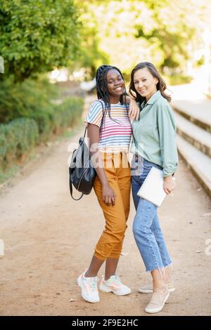 Zwei multiethnische Frauen posieren zusammen mit farbenfroher Freizeitkleidung Stockfoto