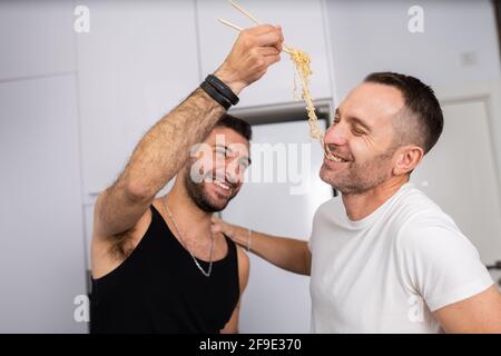 Mann Fütterung Pasta zu seinem Freund in einer lustigen Weise Stockfoto