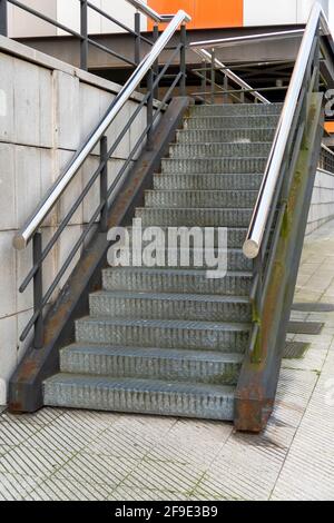 Wellblechtreppe mit glänzenden Chromgeländern. Rostige Rahmenbalken. Nahaufnahme. Industriekonzept Stockfoto