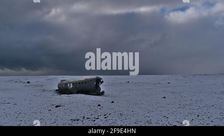 Karge Landschaft mit dem berühmten Wrack eines DC-3-Flugzeugs am Strand von Sólheimasandur an der Südküste Islands in der Wintersaison mit Schnee. Stockfoto