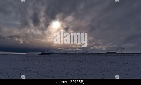 Atemberaubender Blick auf die schneebedeckte Landschaft mit Strommasten an der Südküste Islands bei Jökulsárlón mit dem Öræfajökull-Gebirge. Stockfoto