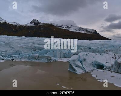 Blick auf den Abbruchrand von Svínafellsjökull, einem Auslaufgletscher der Eiskappe Vatnajökull in Südisland, mit Gletschersee und Gletscherspalten. Stockfoto