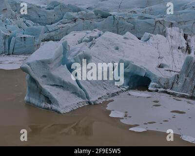 Nahaufnahme der Abbruchkante des mächtigen Gletschers Svínafellsjökull, gelegen im Vatnajökull Nationalpark im Süden Islands, mit Schollen auf dem See. Stockfoto