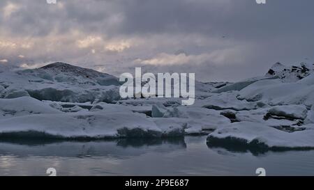 Schöne Aussicht auf schwimmende Eisberge an der Gletscherlagune Jökulsárlón, die sich im Süden Islands im Vatnajökull-Nationalpark mit schneebedeckten Bergen befindet. Stockfoto