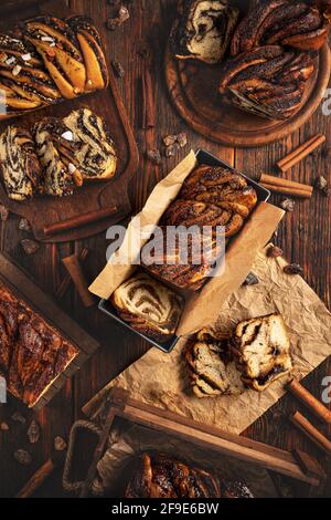 Stillleben von verschiedenen Arten von Babka oder süßen Brioche Brot auf dunklem Holzhintergrund Stockfoto