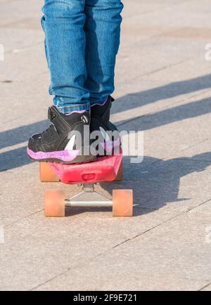 Nahaufnahme mit den Füßen eines Mannes in Sneakers auf einem Skateboard. Stockfoto