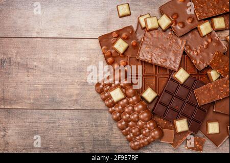 Draufsicht auf Stücke von Schokolade mit Schokoladenstückchen auf rustikalem Holztisch Hintergrund. Schokoladenstücke auf Holztisch. Kopierraum. Draufsicht Stockfoto