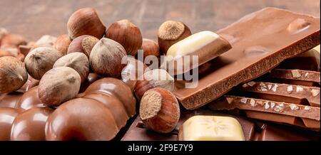 Schokoriegel mit Nüssen. Stapel Haselnussschokolade. Zusammensetzung von Riegel und Stücken von verschiedenen Milch und dunkle Schokolade mit Haselnüssen Stockfoto