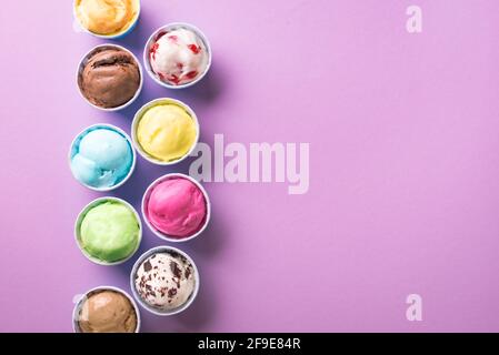 Eiscreme-Sortiment. Verschiedene Eiscreme oder Eis auf violettem Hintergrund, Platz kopieren. Gefrorener Joghurt in kleinen Tassen - gesundes Sommerdessert. Stockfoto