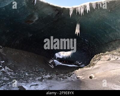 Atemberaubende Aussicht auf den Eingang der Sapphire-Eishöhle im Breiðamerkurjökull-Gletscher, Nationalpark Vatnajökull, Südisland mit stehenden Menschen. Stockfoto