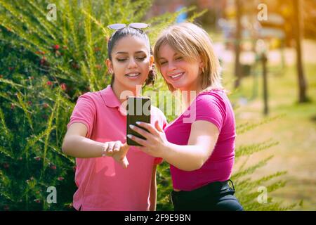 Die beiden spanischen Frauen in einem Park machen ein Selfie An einem sonnigen Tag Stockfoto