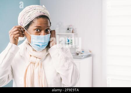 Afroamerikanische reife Patientin mit Gesichtsmaske, die während des Coronavirus-Ausbruchs am Klinikbett auf einen Termin wartet Stockfoto