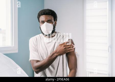 Afroamerikanischer Mann, der Baumwolle mit Alkohol desinfizierendem Arm hält Nach einem kovidierten Impfverfahren in der Klinik während des Coronavirus-Ausbruchs Stockfoto
