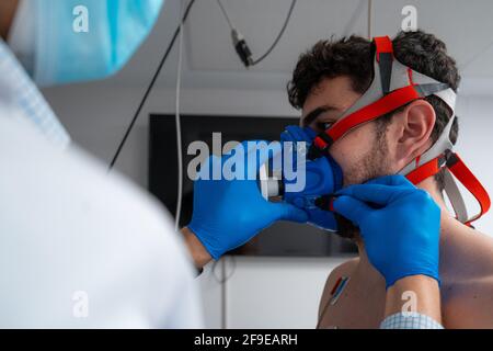 Nicht erkennbarer Arzt, der während der Behandlung eine Maske auf das Gesicht des Patienten aufsetzt Vorbereitung auf den Herzbelastungstest in einem modernen Krankenhaus Stockfoto