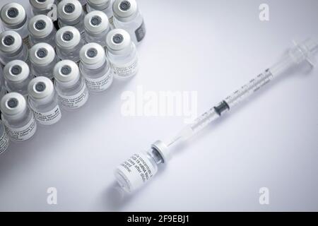 Nahaufnahme einiger Fläschchen mit dem Coronavirus-Impfstoff zusammen mit Eine Nadel auf weißem Hintergrund Stockfoto