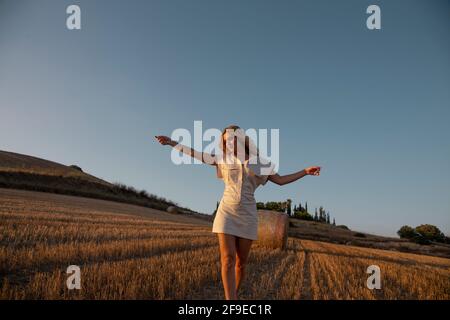 Junge lächelnde Frau im Sommer Outfit und Strohhut zu Fuß am Sandstrand Praia das Furnas in der spanischen Region Galicien im Sommer sonnigen Tag Stockfoto