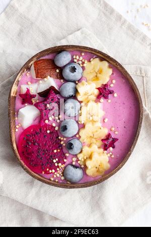 Von oben der Power-Schüssel voll von leckeren Smoothie in der Nähe Reife Bananen- und Drachenfrucht-Scheiben mit Heidelbeeren zum Frühstück Stockfoto