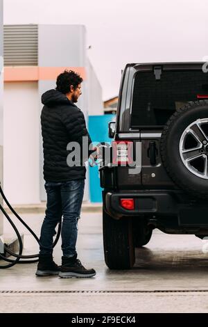 Seitenansicht eines Mannes, der sein Offroad-Auto betankt Eine Tankstelle Stockfoto