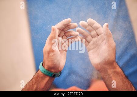 Von oben der Ernte nicht erkennbar männlichen Kletterer mit den Händen in Talkum im modernen Boulderclub Stockfoto