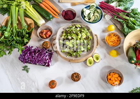 Draufsicht auf ganze und schneiden sortierte Gemüse für Salat Vorbereitung auf Marmortisch Stockfoto