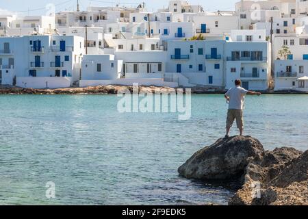 Naoussa, Paros Island, Griechenland - 27. September 2020: Mann beim Angeln am Wasser der Stadt. Kleiner Fischerort. Stockfoto