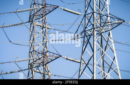 Detail der Strommasten vor einem blauen Himmel, die das britische Stromnetz und die Stromversorgung darstellen Stockfoto