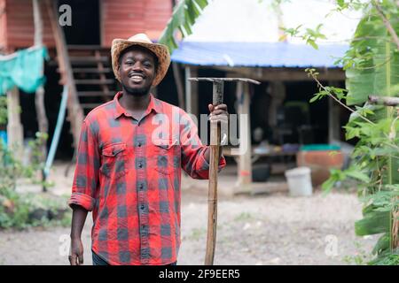 Glück afrikanischer Bauer steht mit seinem Bauernhaus in der Hintergrund Stockfoto