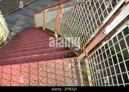 Verrostete alte Stufen führen hinunter zu einer kleinen Brücke Stockfoto