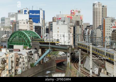 Zwei Züge der Serie E231-500 auf der Chuo Soba-Linie in der Nähe des Bahnhofs Ochanomizu mit Akihabara im Hintergrund. Tokio, Japan. Stockfoto