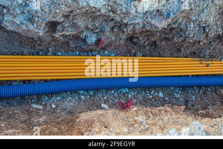 Verlegung der Kommunikation, Versorgung von Gebäuden mit Wasser und Strom unter dem Boden, einem nicht abgedeckten Graben und einem Rohrverbindungsabschnitt Stockfoto