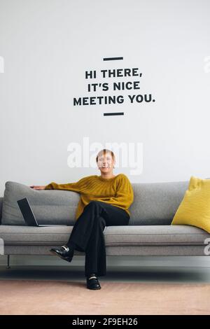 Geschäftsfrau mit Laptop auf Sofa in der Bürolobby. Erfolgreicher Freiberufler, der im Büro auf dem Sofa sitzt. Stockfoto