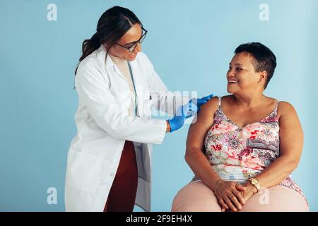 Gesundheitsfachkraft, die ältere Frauen mit Grippeschutzimpfung behandelt. Arzt, der einer älteren Frau in der Klinik einen Impfstoff verabreicht. Stockfoto