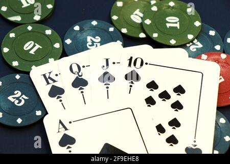 Eine Nahaufnahme von Spaten Royal Flush Karten und Poker Chips auf dem blauen Pokerkarten-Spieltisch Stockfoto