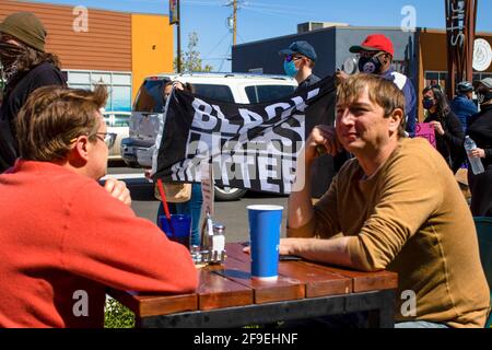 Reno, Usa. April 2021. Demonstranten mit einer BLM-Flagge passieren während des marsches ein Essen im Freien.Demonstranten versammeln sich, um solidarisch mit anderen BLM-Demonstranten (Black Lives Matter) im ganzen Land zu marschieren. Während die Gruppe von einigen, die sie vorbeikamen, in Gefechtet wurde, blieb der marsch friedlich. Kredit: SOPA Images Limited/Alamy Live Nachrichten Stockfoto