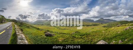 Großes Panorama mit Straße in Molls Gap, Owenreagh River Valley, MacGillycuddys Reeks Berge und Farmen, Wild Atlantic Way, Ring of Kerry, Irland Stockfoto