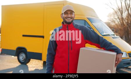 Indischer Mann, der Paket liefert. Pappkarton vor dem Van halten. Hochwertige Fotos Stockfoto