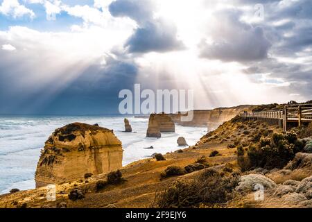 Sonnenstrahlen durch Wolken, die auf die Felsformationen der Twelve Apostles an der Great Ocean Road, Victoria, Australien, scheinen Stockfoto